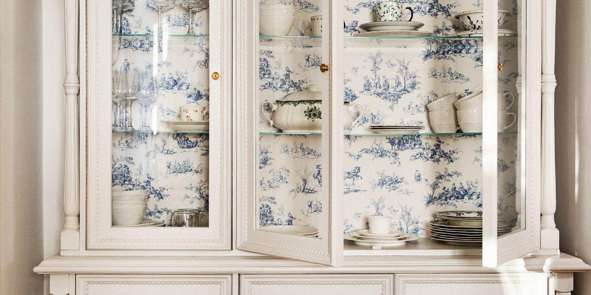 porcelanowe naczynia ustawione w białym kredensie w stylu cottage